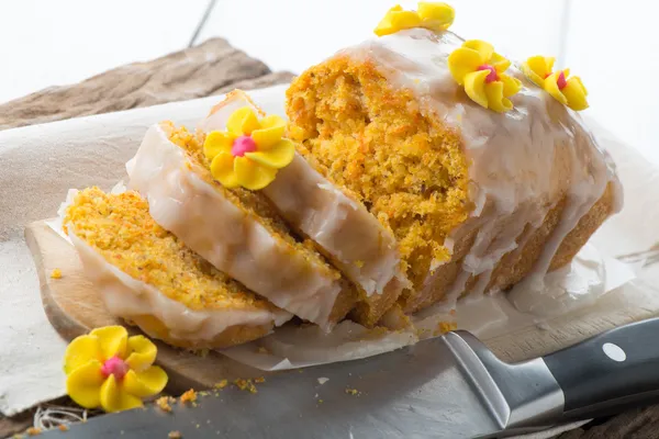 Sliced carrot cake with icing flowers — Stock Photo, Image