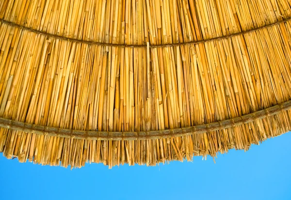 Sombrilla de paja de playa sombrilla contra el cielo azul — Foto de Stock