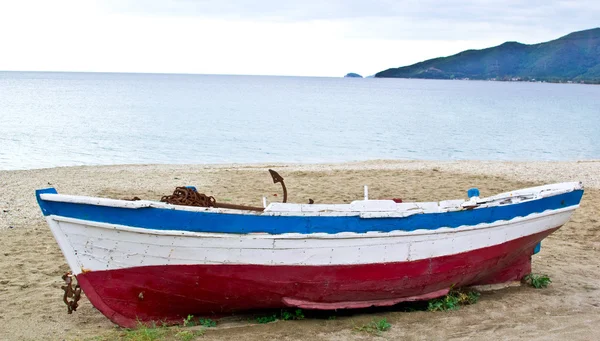 Barco de pesca en arena con cielo azul nublado y agua — Foto de Stock