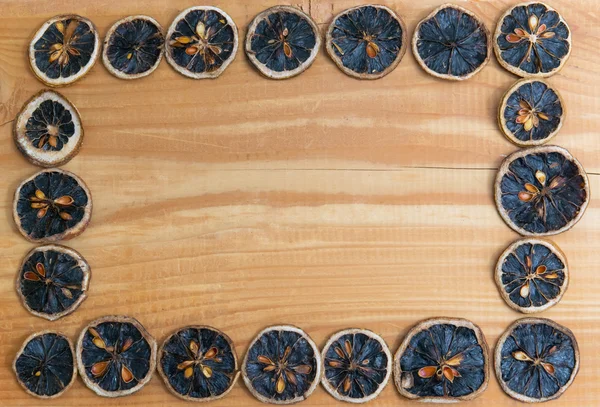 Randen van het frame van de segmenten van het gedroogde oranje vruchten op hout achtergrond — Stockfoto