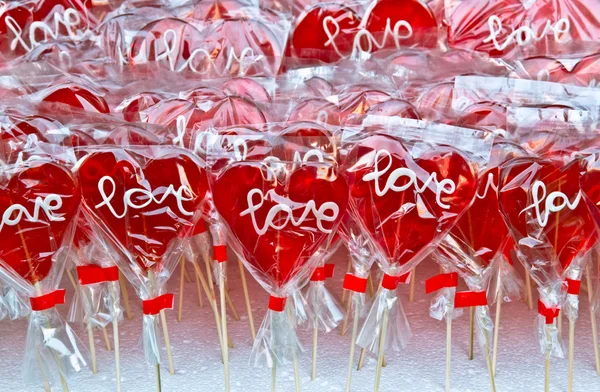 Lecca-lecca a forma di cuore rosso su uno stand di mercato — Foto Stock