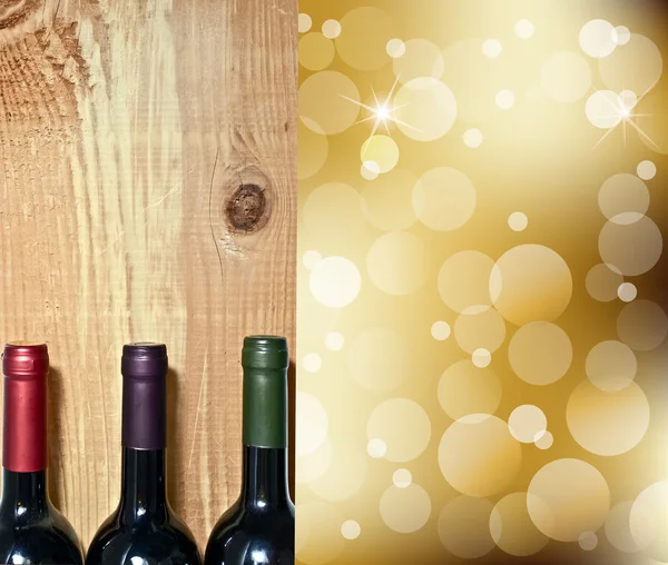 Бутылка вина на деревянном столе и абстрактные огни на фоне золотого шампанского — стоковое фото