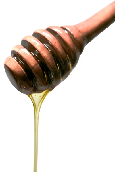 Honey dripping from a wooden dipper isolated on a white background — Stock Photo, Image