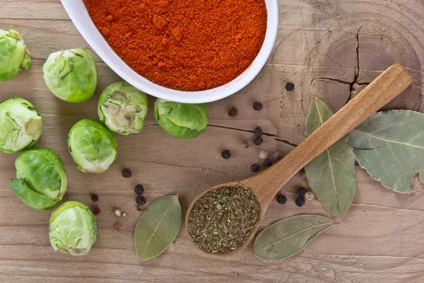 Spices and fresh raw brussels sprouts on a wooden table — Stock Photo, Image