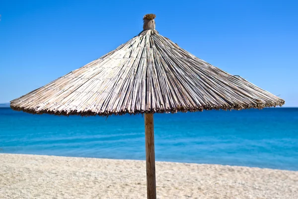 Mavi gökyüzü ile plajda saman şemsiye — Stok fotoğraf