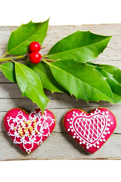 Galletas de jengibre hechas en casa de Navidad y bayas de acebo sobre mesa de madera — Foto de Stock