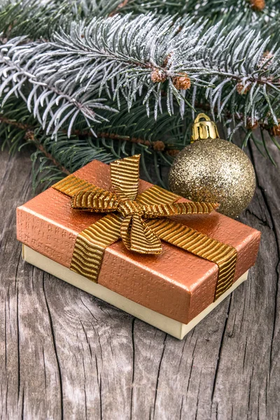 Gift box with golden ribbon and Christmas decoration over wooden table — Stock Photo, Image