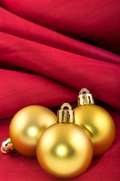 Bola de Natal dourada em um pano de seda vermelho — Fotografia de Stock