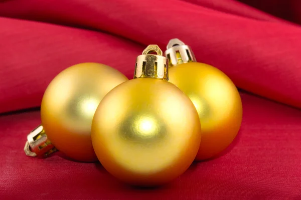 Bola de Natal dourada em um pano de seda vermelho — Fotografia de Stock