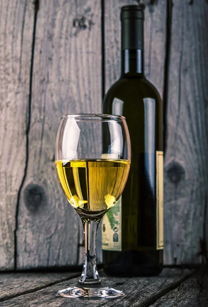 Bottle of white wine and wineglass on old wood backround vintage photo — Stock Photo, Image