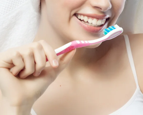 Smiling woman is brushing her teeth