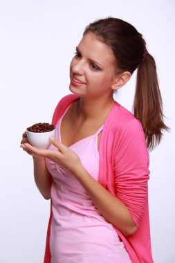 bir fincan kahve çekirdekleri tutan genç kadın