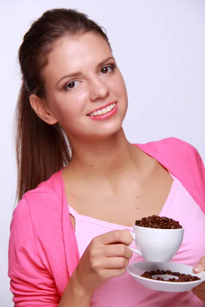 Молода жінка тримає чашку кавових зерен — стокове фото