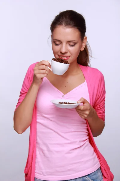 Mujer joven sosteniendo una taza de granos de café — Foto de Stock