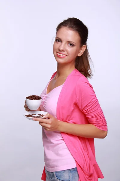 Mujer joven sosteniendo una taza de granos de café — Foto de Stock