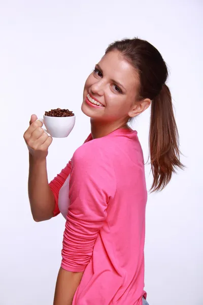 Mujer joven sosteniendo una taza de granos de café — Foto de Stock