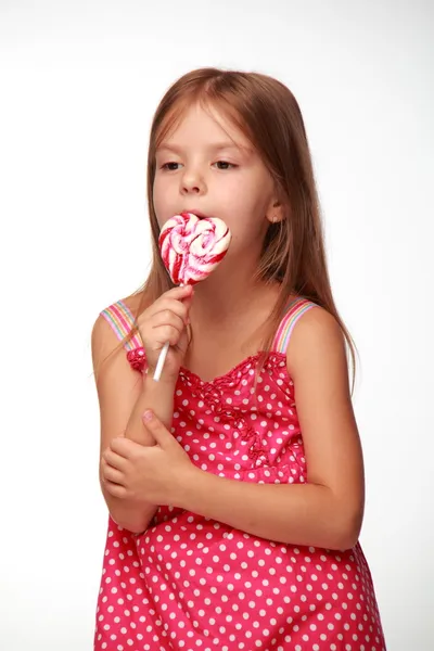 Liten flicka i rosa klänning med lollipop — Stockfoto