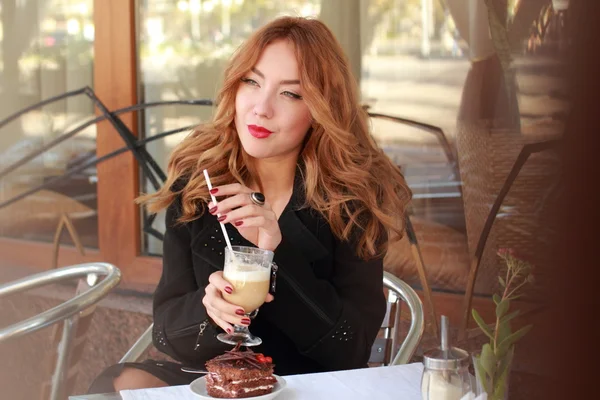 Vacker flicka dricker en latte på en restaurang — Stockfoto