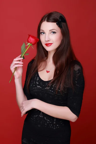 Flicka med en ros på en röd bakgrund — Stockfoto