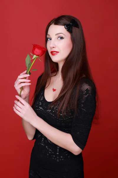 Chica con una rosa sobre un fondo rojo — Foto de Stock