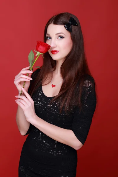 Chica con una rosa sobre un fondo rojo — Foto de Stock