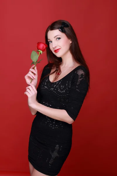 Ragazza con una rosa su uno sfondo rosso — Foto Stock