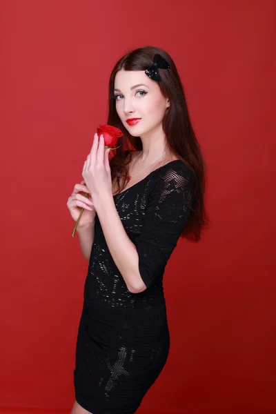 Mädchen mit einer Rose auf rotem Hintergrund — Stockfoto