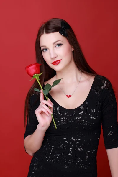 Menina com uma rosa em um fundo vermelho — Fotografia de Stock