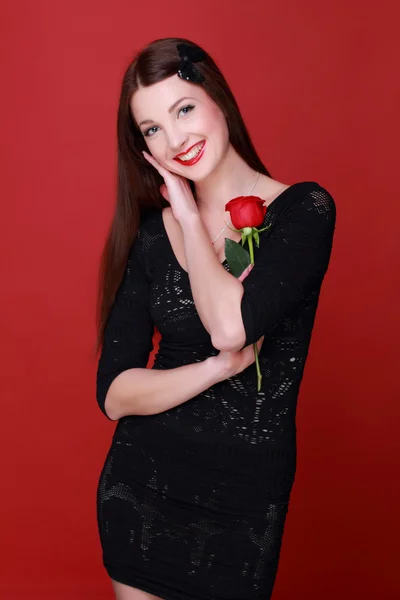 Menina com uma rosa em um fundo vermelho — Fotografia de Stock