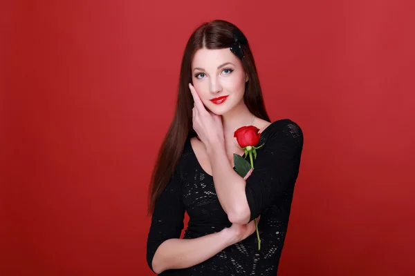 Dívka s růží na červeném pozadí — Stock fotografie