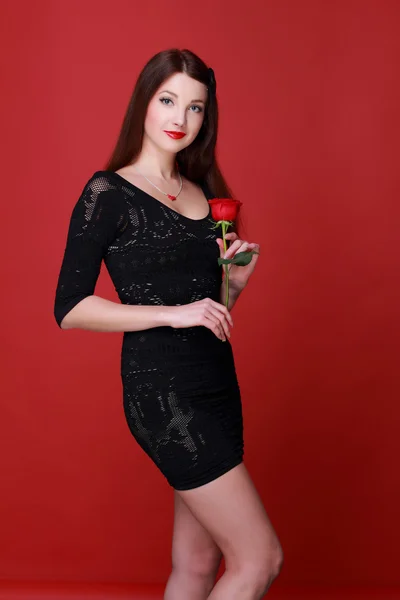 Flicka med en ros på en röd bakgrund — Stockfoto