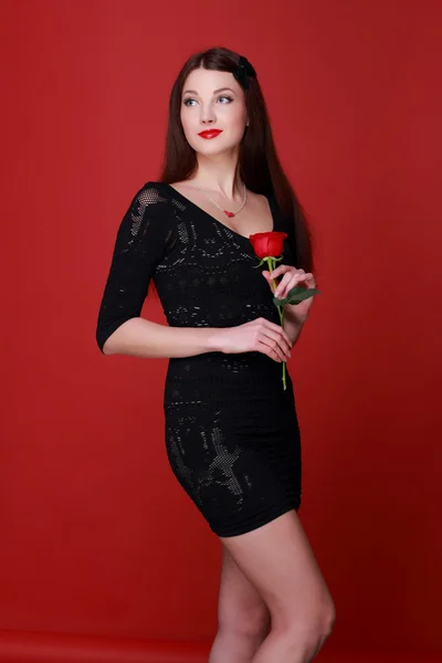 Ragazza con una rosa su uno sfondo rosso — Foto Stock