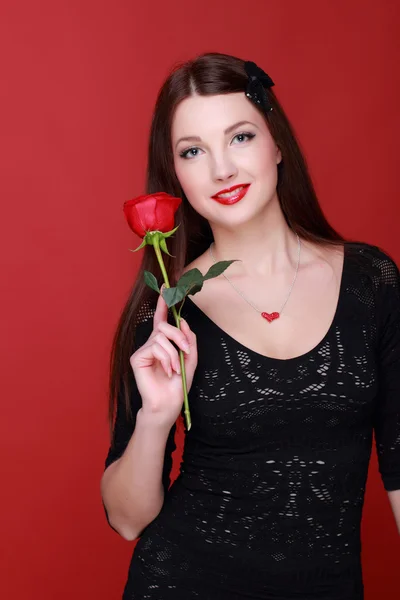 Mädchen mit einer Rose auf rotem Hintergrund — Stockfoto