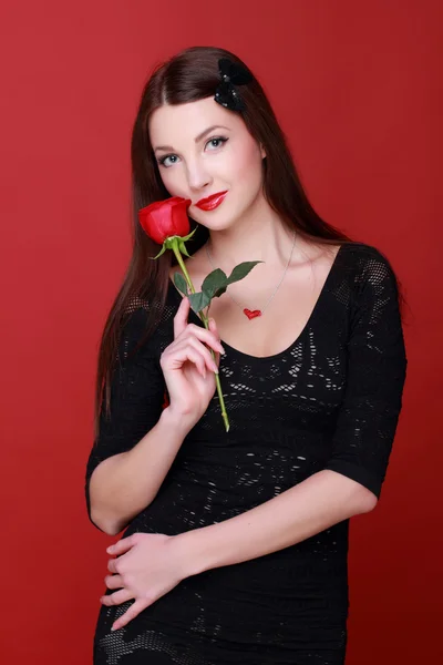 Chica con una rosa sobre un fondo rojo — Foto de Stock