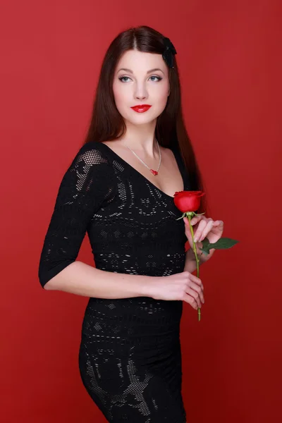 Menina com uma rosa em um fundo vermelho — Fotografia de Stock