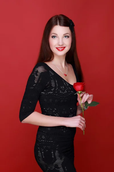 Mädchen mit einer Rose auf rotem Hintergrund — Stockfoto