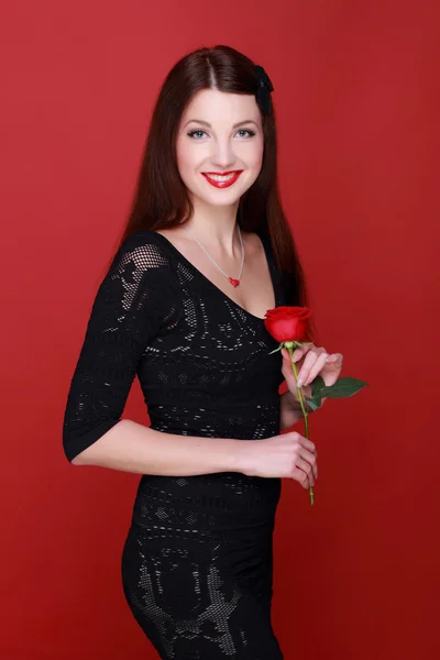 Chica con una rosa sobre un fondo rojo — Foto de Stock