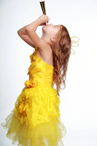 Klein meisje in een gele jurk en een kroon — Stockfoto