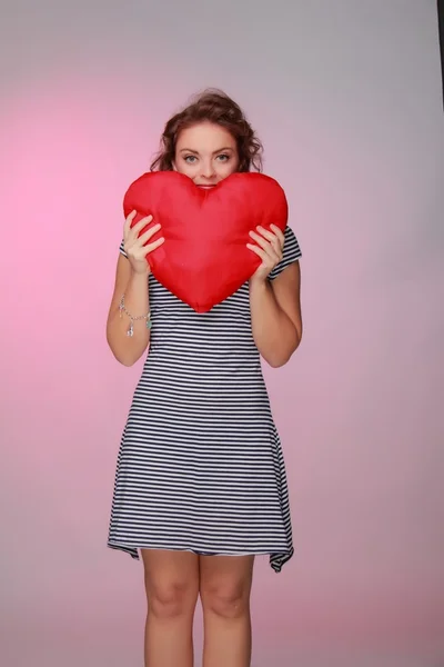 Beautiful woman in a striped dress holding a big heart — Stock Photo, Image