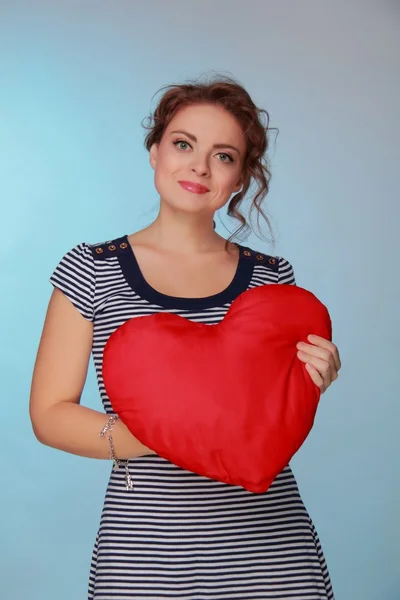 Beautiful woman in a striped dress holding a big heart — Stock Photo, Image