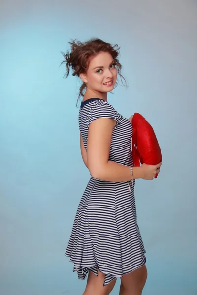 Beautiful woman in a striped dress holding a big heart — Stock Photo, Image