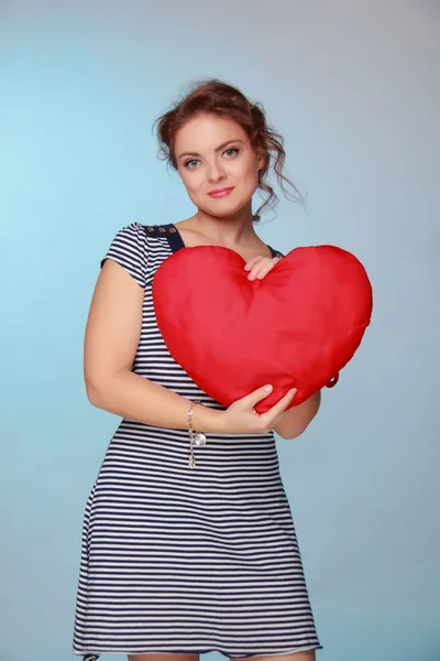 Beautiful woman in a striped dress holding a big heart — Stock Photo, Image