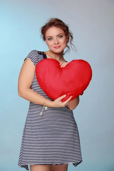 Beautiful woman in a striped dress holding a big heart — Stock Photo, Image