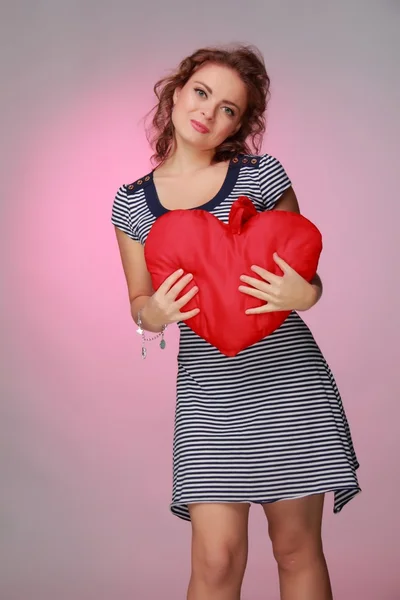 Krásná žena v pruhovaných šatech drží velké srdce — Stock fotografie
