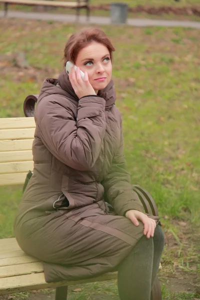 Mulher em um banco falando ao telefone — Fotografia de Stock