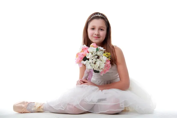 Jeune ballerine assise en position ballet tenant les fleurs — Photo