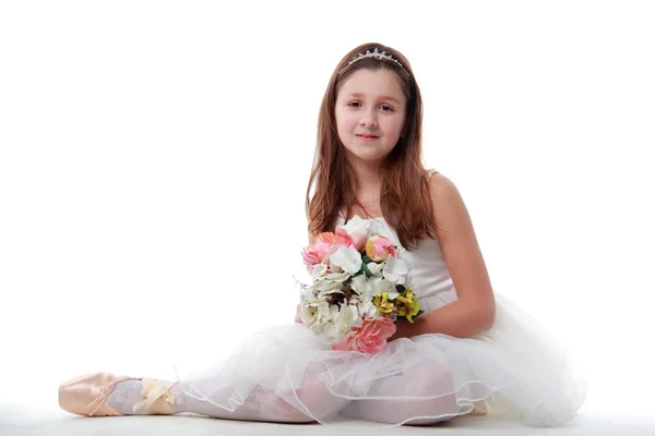 Jeune ballerine assise en position ballet tenant les fleurs — Photo