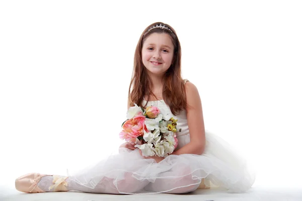 Jeune ballerine assise en position ballet tenant les fleurs — Photo