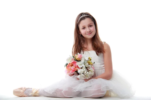 Jeune ballerine assise en position ballet tenant les fleurs — Photo