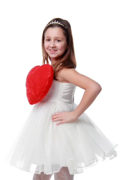 A little girl in a white dress holding a red heart symbol — Stock Photo, Image